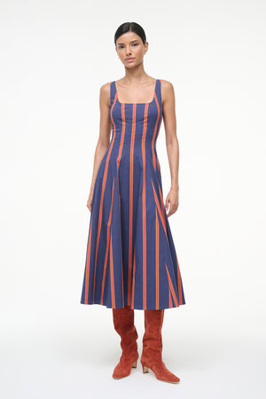 Woman wearing a blue and orange striped sleeveless midi dress with auburn suede boots. 