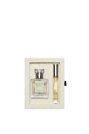 A luxury gift set containing a rectangular glass perfume bottle and a slim cylindrical vial, both with silver caps, presented inside a cream-colored box with gold foil detailing.