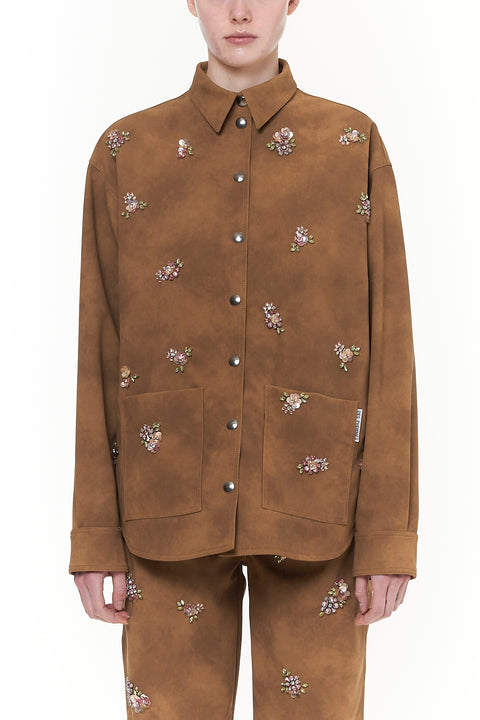 Brown leather workwear jacket with floral embellishments and silver snap closure. 