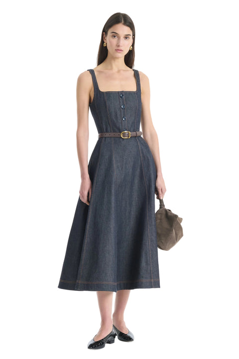 Woman wearing a dark denim dress with a belt on a white background