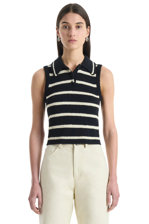 Woman wearing a black and white striped sleeveless top with collar with beige pants on a white background