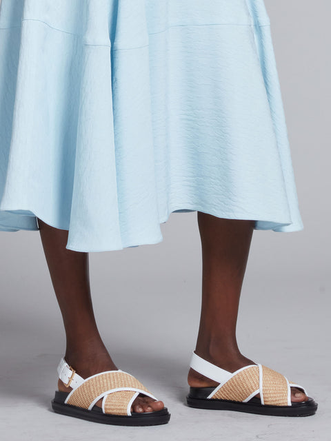 Bottom half of model wearing the fussbett criss cross sandals with raffia effect fabric.