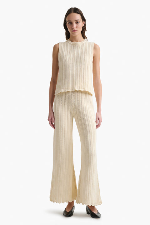 Woman wears cream knitted wide leg pant with scalloped hem and matching tank top.