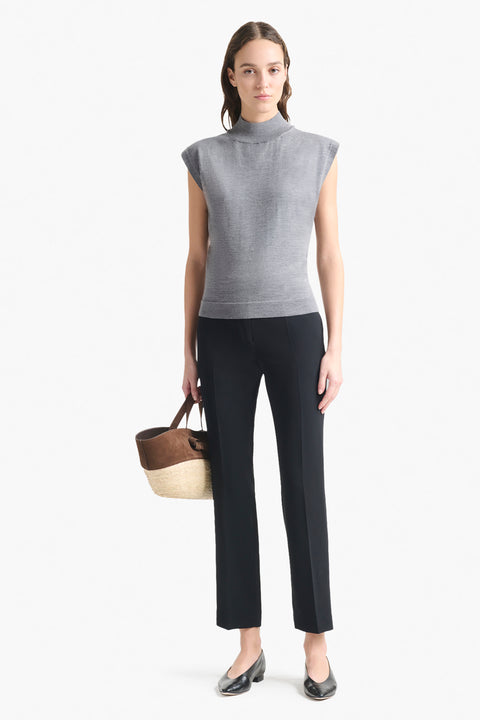 Woman wears grey cap sleeve turtleneck  sweater top with black pants.