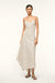Woman wearing a v-neck ivory with brown stripes maxi dress that features a side pleat and ruching at the hip, paired with brown sandals. 