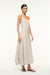 Side angle of a woman wearing a v-neck ivory with brown stripes maxi dress that features a side pleat and ruching at the hip, paired with brown sandals. 