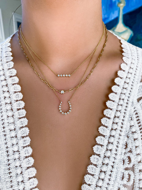 Models neck and chest wearing multiple gold and diamond necklaces.