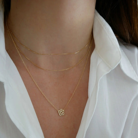 Rose necklace in yellow gold and diamonds shown on a models neck.