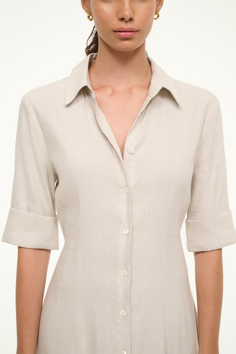 Close up of a woman wearing a cream linen maxi dress that features half sleeves, a collar, and button down detail down he front.