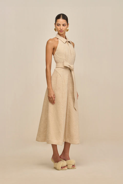 Woman wearing a beige sleeveless dress with a belt on a beige background