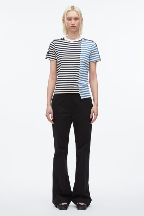 Woman wears patchwork t-shirt with light blue and navy stripes with black pants.