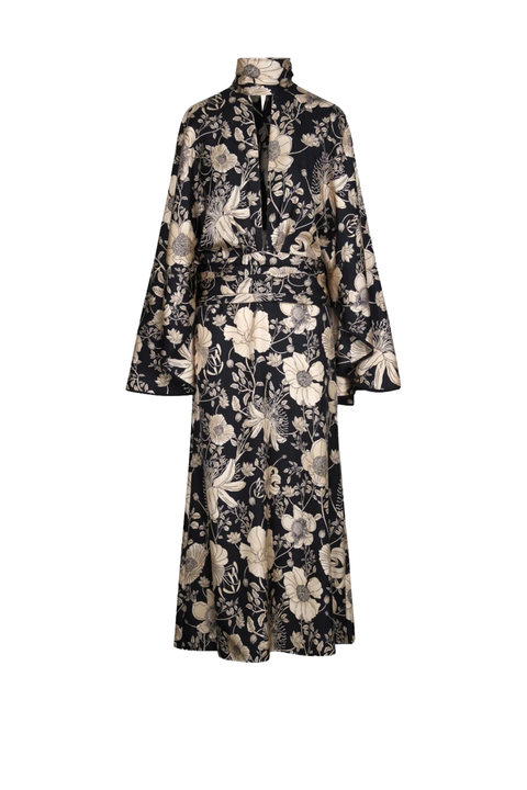 A long-sleeved midi dress with a high collar and a matching waist tie, featuring an all-over floral pattern in beige and cream on a black background, shown against a plain white background.