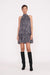 Full body view of a model facing the camera in the black and white wavy dot high neck mini dress