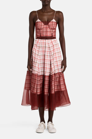 Full body view of a model facing the camera in the plaid a-line skirt with sheer detailing on the bottom hem