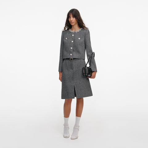 Woman posing wearing a gray jacket with crystal buttons and collar with a matching midi skirt on a white background