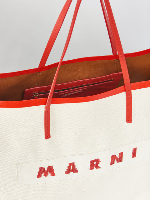 Up close of the top of janis tote bag with red leather straps.