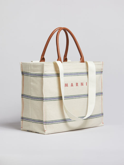Marni medium tote facing sideways, showing the side of the tote and longer fabric straps.