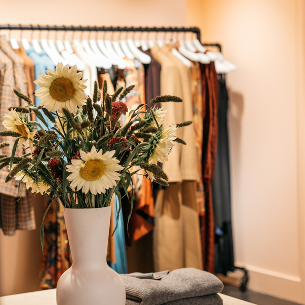 Shot of flower arrangement and clothing on hanging rack in the ALC space in Market Highland Park Dallas.