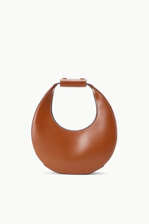 Small brown leather handbag in the shape of a moon with white stitching. 
