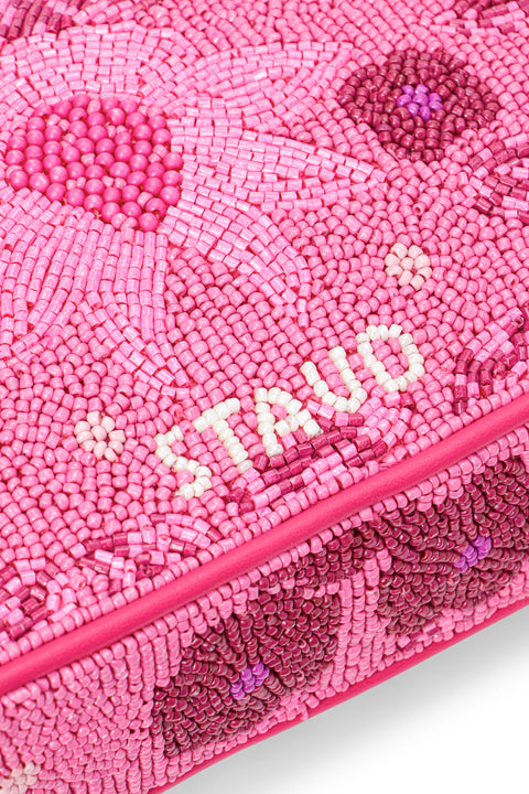 Detail shot of the back of a two-tone, hot pink beaded shoulder bag that features floral designs and appliques, with the brand name in white contrast beading. 