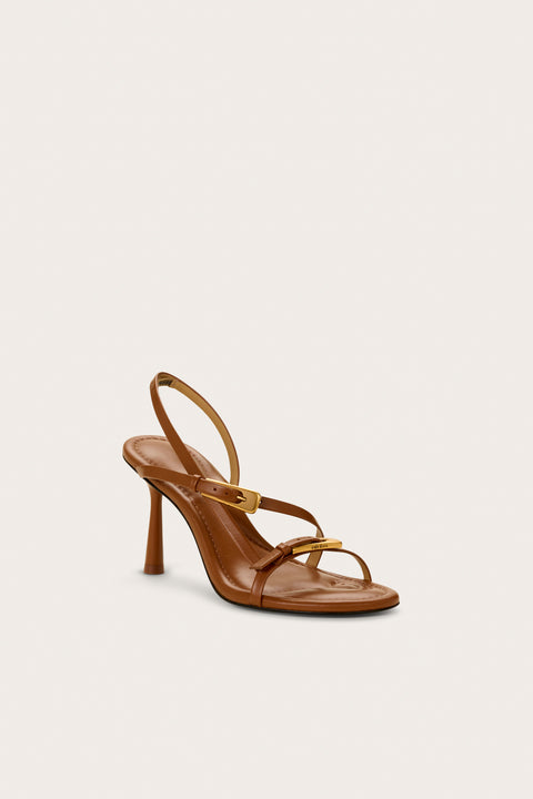Front view of a brown strappy heel that features two gold buckle details and a slingback strap. 