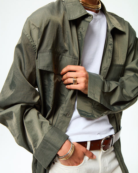 Woman wearing a silver-toned, tubular collar necklace with other pieces of jewelry. 