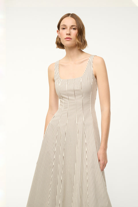 Close up of a woman wearing a midi dress that boasts a square neck, corset-style bodice, full, and full A-line skirt in a cream and brown micro stripe pattern.
