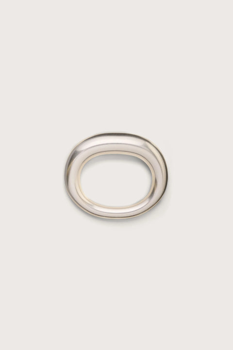 A silver toned tubular bangle that features an asymmetrical thicker side. 