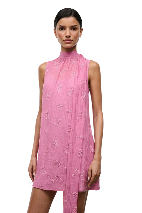 A woman wearing a pink high neck mini dress with beaded embellishments close-up angle