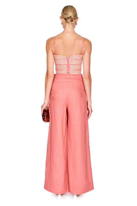 Woman wearing a pink outfit with a white strapless top and wide-leg pants on a white background