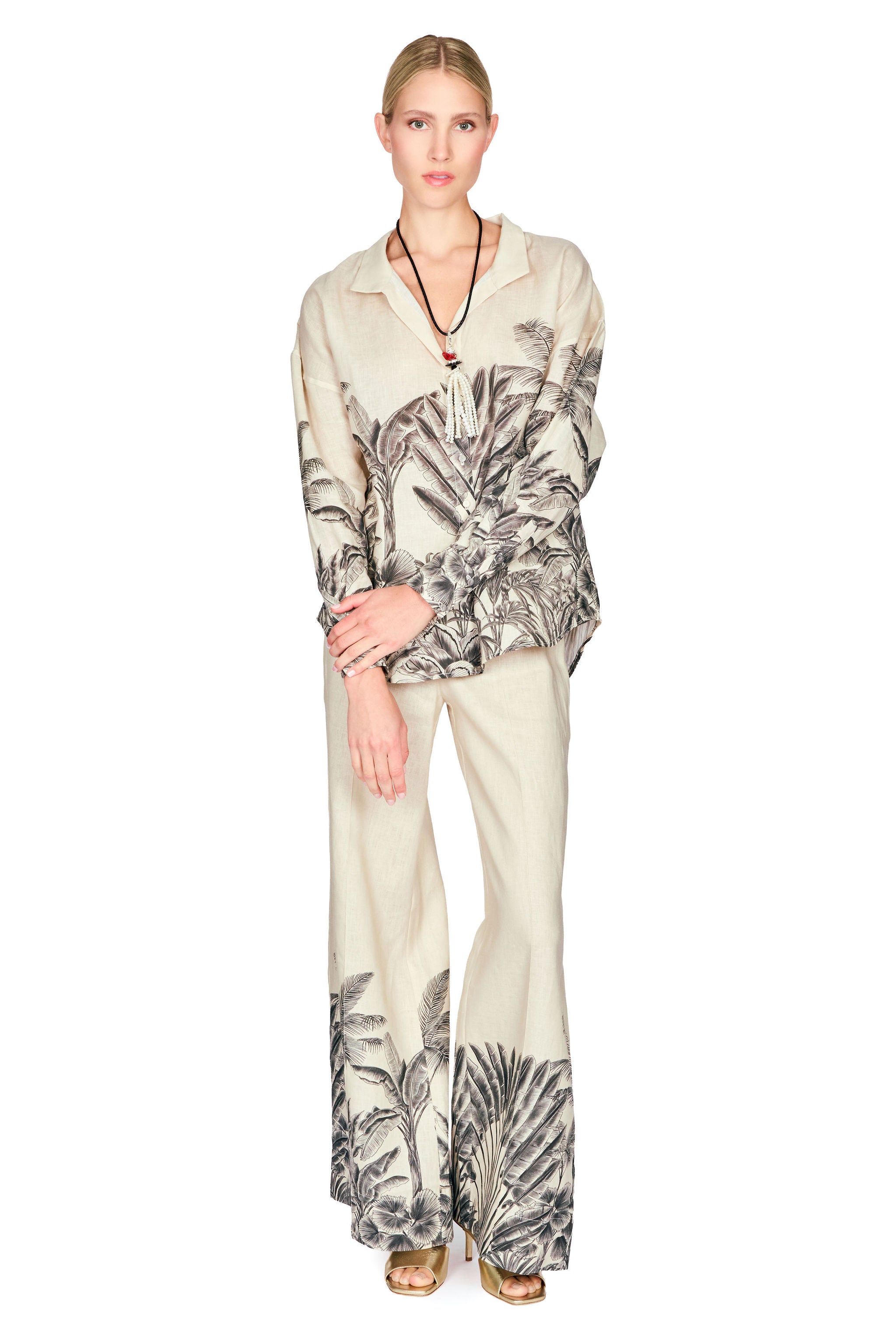 Woman wearing a patterned button down blouse and long pants on a white background