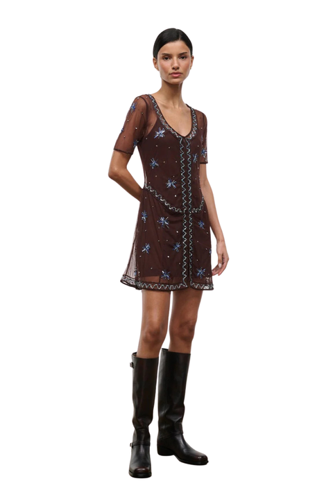 Woman wearing a brown sheer mini dress with embellishments on a white background