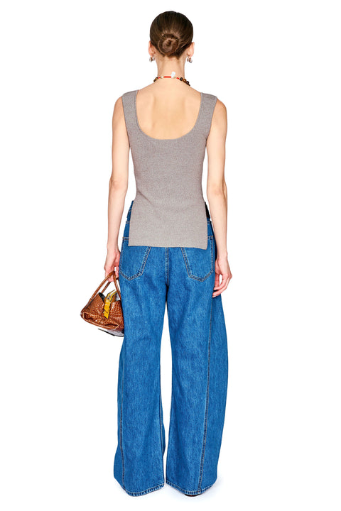 A woman shown from the back wearing a gray ribbed tank top and wide-leg blue denim jeans, holding a brown leather handbag against a plain white background.