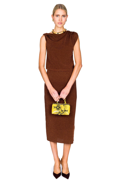 Woman wearing a brown dress clutching her yellow handbag in front with a white background
