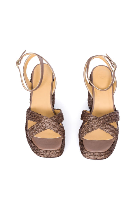 Frontal view of brown woven sandal with a platform sole on a white background