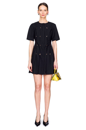 Woman wearing a short black origami dress with a yellow snakeskin bag.