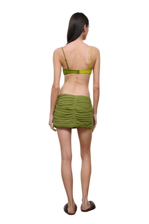 Woman wearing a green mini skirt cover up set on a white background back angle