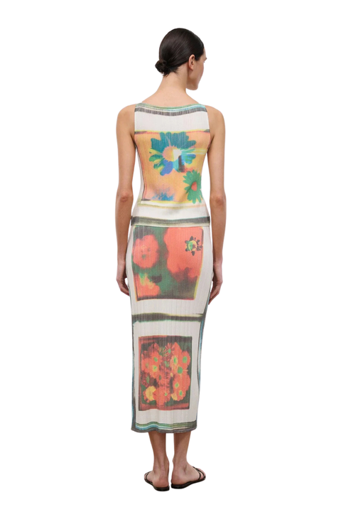 Woman wearing a floral patterned two piece skirt set on a white background back angle