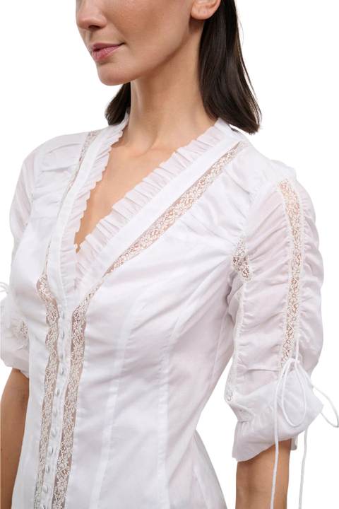 Close-up of a woman wearing a white button-up top with cinched sleeves and lace detailing