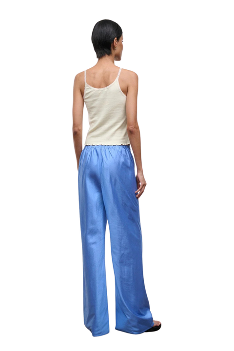 A back angle of a woman wearing bright blue silk trousers 