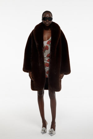 Model facing camera wearing Giuseppe faux fur maxi jacket in brown